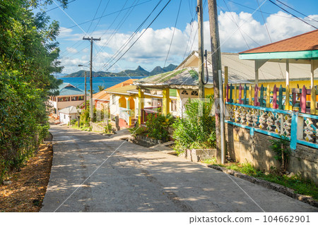 Colorful street with residential houses at the bay, of Mayreau island with Union island in the background, Saint Vincent and the Grenadines, West Indies, Caribbean Colorful street with residential houses at the bay, of Mayreau island with Union island in the background, Saint Vincent and the Grenadines, West Indies, Caribbean 104662901