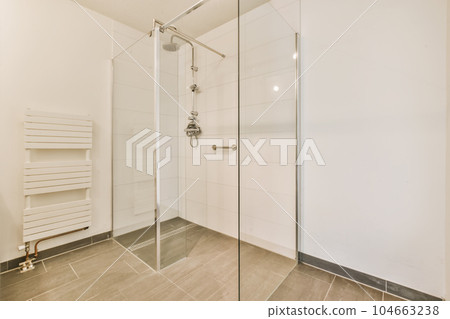 a modern bathroom with white walls and tile flooring, including a walk - in shower stall on the right side 104663238