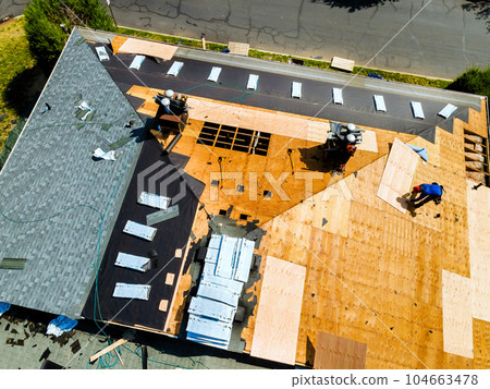 New shingles were installed and old ones were replaced plywood during process of repairing roof of apartment building. New shingles were installed and old ones were replaced plywood during process of repairing roof of apartment building. 104663478