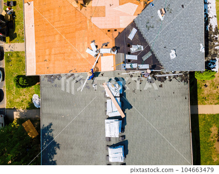 Installation new shingles and replacement of old ones plywood took place during repair of apartment buildings roof. Installation new shingles and replacement of old ones plywood took place during repair of apartment buildings roof. 104663479