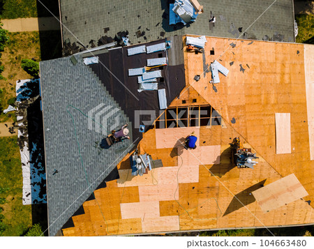 During repair work on apartment buildings roof old shingles were replaced plywood and new shingles were installed. 104663480