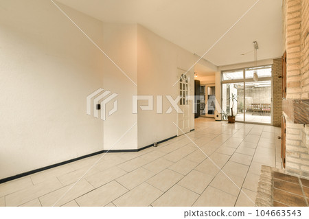 an empty living room with white walls and floor tiles on the floor, there is a fireplace in the corner 104663543