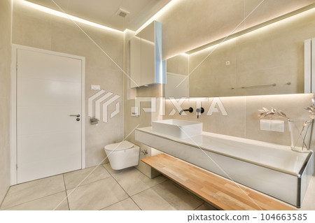 a bathroom with a sink, toilet and mirror on the wall in it's back lit lighting above is an open white door 104663585
