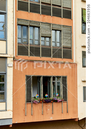 Lgbt signs on a window of appartment of residential building. Rainbow flag LGBTQ community support symbol on a balcony in Barcelona, Spain, Europe. LGBT Rainbow Sign Balcony, Old Town. 104663936