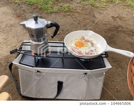 室外兩個燃燒器上放著一杯咖啡和一個煎鍋煎雞蛋 室外兩個燃燒器上放著一杯咖啡和一個煎鍋煎雞蛋 104665806