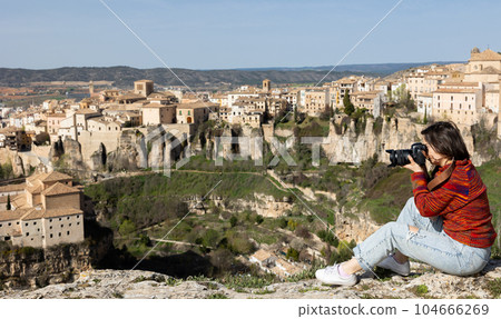 Woman tourist with camera on background of buildings of the Spanish city of Cuenca 104666269