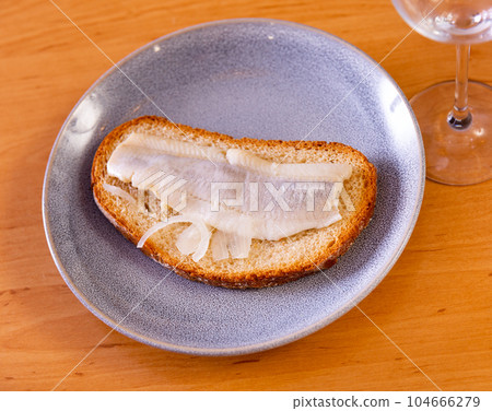 Marinated herring and onion sandwich served on plate 104666279