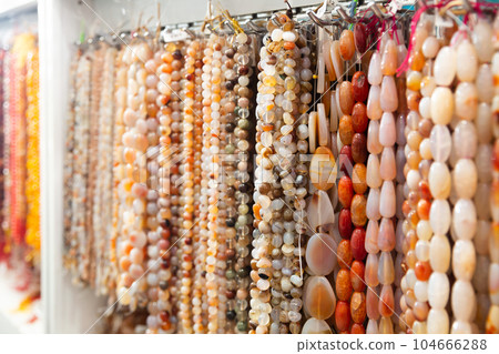 Beads from various semi-precious stones at the stand of jewelry store 104666288