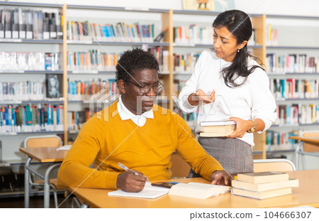 Portrait of librarian handing book to man Portrait of librarian handing book to man 104666307
