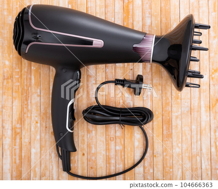 Black blow dryer on wooden surface Black blow dryer on wooden surface 104666363