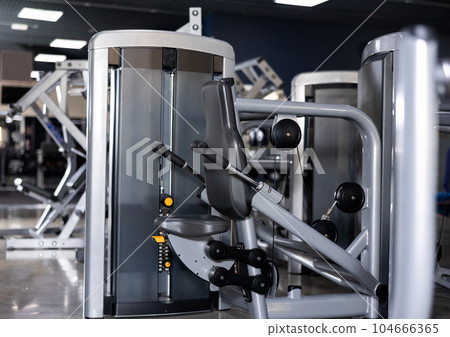 Shiny new triceps press machine in middle of gym 104666365
