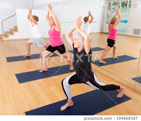 Mature women practicing yoga perform an exercise in the warrior pose I Mature women practicing yoga perform an exercise in the warrior pose I 104666587