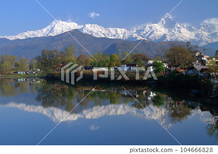 Pokhara, Nepal in South Asia View of Machapuchare and Annapurna mountain range from the dam side and the water mirror of Fewa Lake 104666828