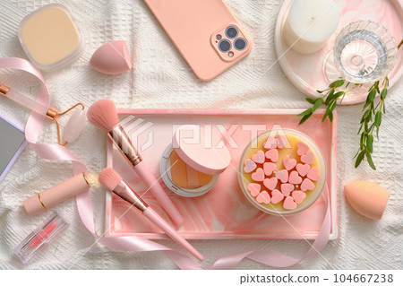 Lovely pink concept with a rectangle tray featured scented candle, cushion compact, makeup brushes and other makeup stuffs displayed. Makeup products mockup Lovely pink concept with a rectangle tray featured scented candle, cushion compact, makeup brushes and other makeup stuffs displayed. Makeup products mockup 104667238