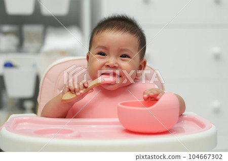 happy infant baby eating food itself with spoon at home happy infant baby eating food itself with spoon at home 104667302