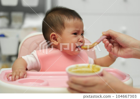 mother feeding food to her crying infant baby with spoon, refuse to eat mother feeding food to her crying infant baby with spoon, refuse to eat 104667303