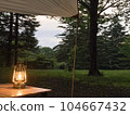 Tarp and lit lantern in the evening forest 104667432