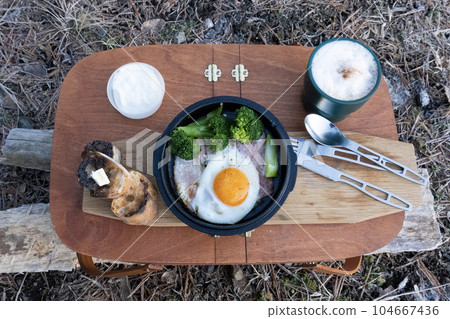 Fried eggs and cappuccino in a wooden basket outdoors Fried eggs and cappuccino in a wooden basket outdoors 104667436