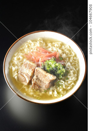 A bird's-eye view of hot Okinawa soba with pork ribs, plenty of small green onions, and red ginger on a black background 104667908