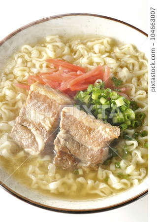 A bird's-eye view of hot Okinawa soba with pork ribs, plenty of small green onions, and red pickled ginger on a white background 104668007