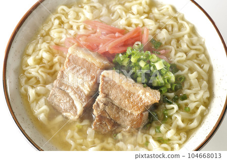 A bird's-eye view of hot Okinawa soba with pork ribs, plenty of small green onions, and red pickled ginger on a white background 104668013