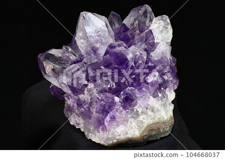 Amethyst druse on a dark background close up. Cluster of lilac crystals Amethyst druse on a dark background close up. Cluster of lilac crystals 104668037