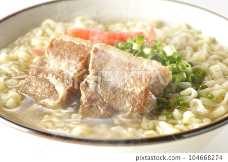 Piping hot Okinawa soba with pork belly, plenty of small green onions and red pickled ginger, photographed against a white background 104668274