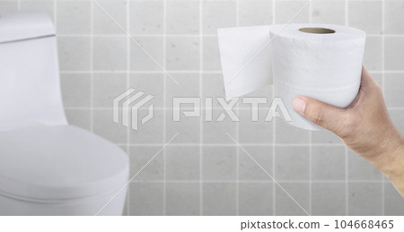 A person suffering from diarrhea holds a roll of toilet paper in front of the toilet bowl 104668465