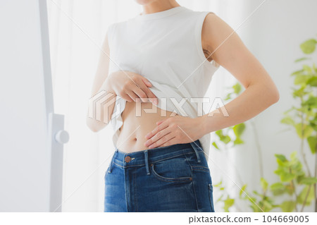 Woman checking her stomach in the mirror Woman checking her stomach in the mirror 104669005