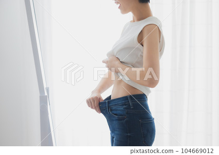 Woman checking her stomach in the mirror 104669012
