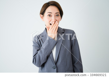 Surprised young woman with her hand over her mouth Business image 104669321