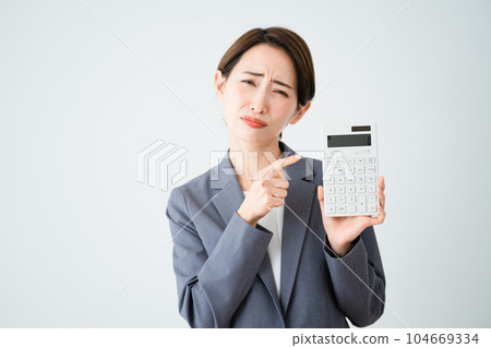 Business image of a young woman holding a calculator and pointing Business image of a young woman holding a calculator and pointing 104669334