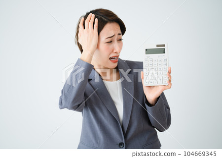 Business image of a young woman holding a calculator and holding her head 104669345