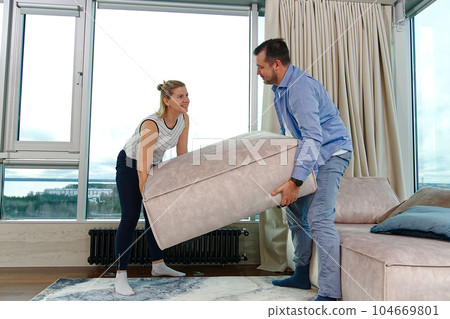 Family rearranging furniture Happy couple moving furniture in new apartment. Moving day happy buyers Family rearranging furniture Happy couple moving furniture in new apartment. Moving day happy buyers 104669801