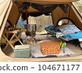 Cot, wood stove, wood basket and wood table in the tent 104671177