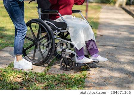 Nursing home. Young caregiver helping senior woman in wheelchair. Nursing home. Young caregiver helping senior woman in wheelchair. 104671306