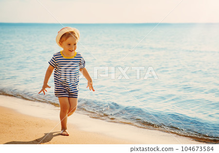 Little boy running along water's edge by the sea. Little boy running along water's edge by the sea. 104673584