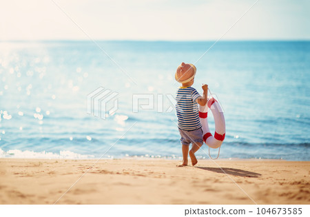 Little boy with lifebuoy in his hands walking alone seaside. Little boy with lifebuoy in his hands walking alone seaside. 104673585