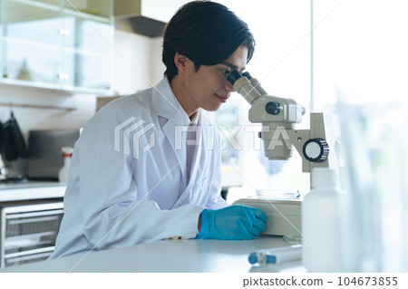 Male scientist observing with a microscope Male scientist observing with a microscope 104673855