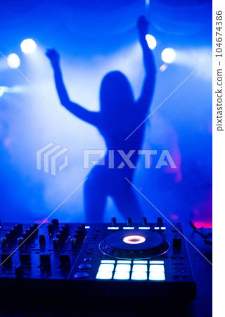 silhouette of young slim dancers on stage ane of focus in night club with DJ mixer silhouette of young slim dancers on stage ane of focus in night club with DJ mixer 104674386