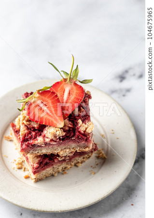 Two pieces of Strawberry granola bars on a pate on white marble background close up. Delisious homemade oat squares for breakfast with copy space Two pieces of Strawberry granola bars on a pate on white marble background close up. Delisious homemade oat squares for breakfast with copy space 104675965