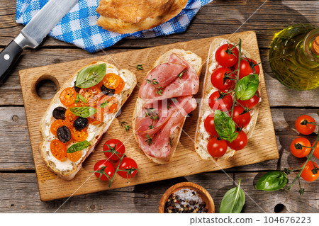 Sandwich set of bruschetta with juicy tomatoes, cheese and prosciutto Sandwich set of bruschetta with juicy tomatoes, cheese and prosciutto 104676223