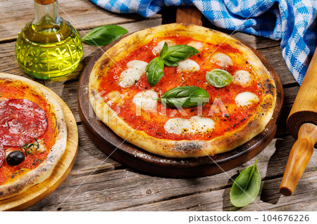 Margarita and pepperoni pizza with tomatoes, mozzarella cheese and basil 104676226