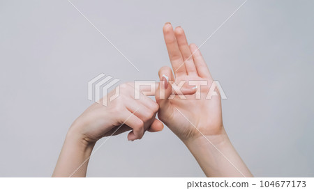 Provocative gesture. Fuck off. Woman hands showing finger in hole isolated on gray free space background. 104677173