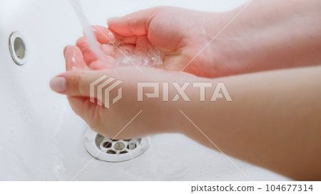 Clean hands. Bacteria prevention. Virus hygiene. Woman washing palms skin with water to protect from microbes infection spreading in white sink. Clean hands. Bacteria prevention. Virus hygiene. Woman washing palms skin with water to protect from microbes infection spreading in white sink. 104677314