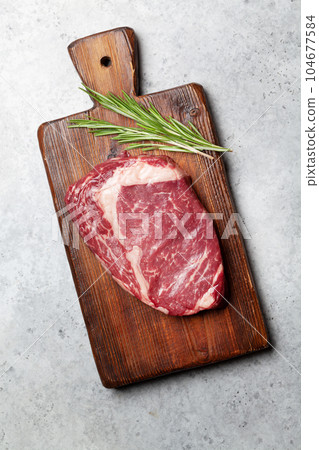 Raw ribeye steak on cutting board Raw ribeye steak on cutting board 104677584