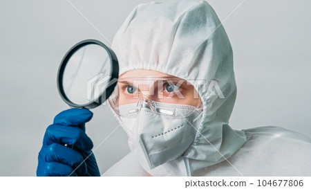 Virology research. Medical examination. Woman doctor laboratory specialist in white protective suit equipment with loupe isolated on grey background. Virology research. Medical examination. Woman doctor laboratory specialist in white protective suit equipment with loupe isolated on grey background. 104677806