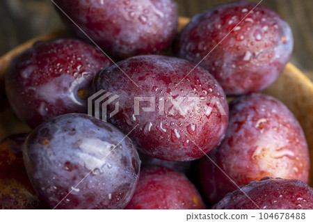 Ripe plums of dark color on the table Ripe plums of dark color on the table 104678488
