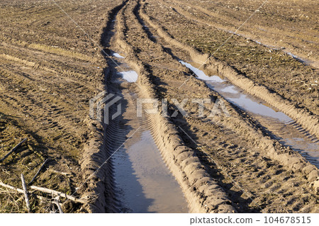 deep ruts from cars in the mud of the field deep ruts from cars in the mud of the field 104678515