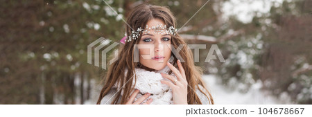 Beautiful bride in a white dress with a bouquet in a snow-covered winter forest. Portrait of the bride in nature Beautiful bride in a white dress with a bouquet in a snow-covered winter forest. Portrait of the bride in nature 104678667
